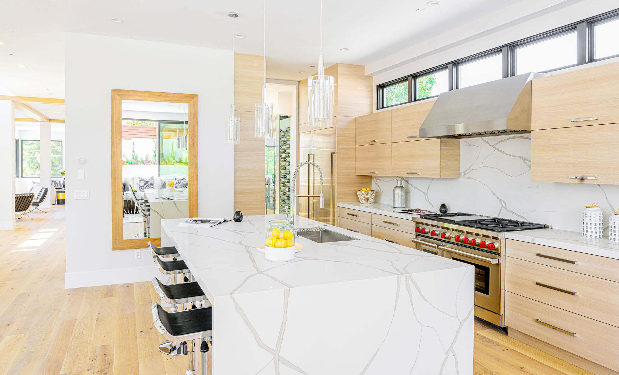 A kitchen island features a statement waterfall quartz design. This adds visual appeal to the kitchen while serving as a functional workspace.