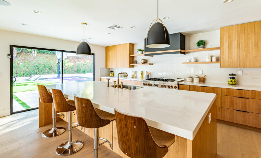 A kitchen has quartz countertops and brown cabinetry and seating.